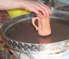 Waxing the bottom of the bisqued pot.